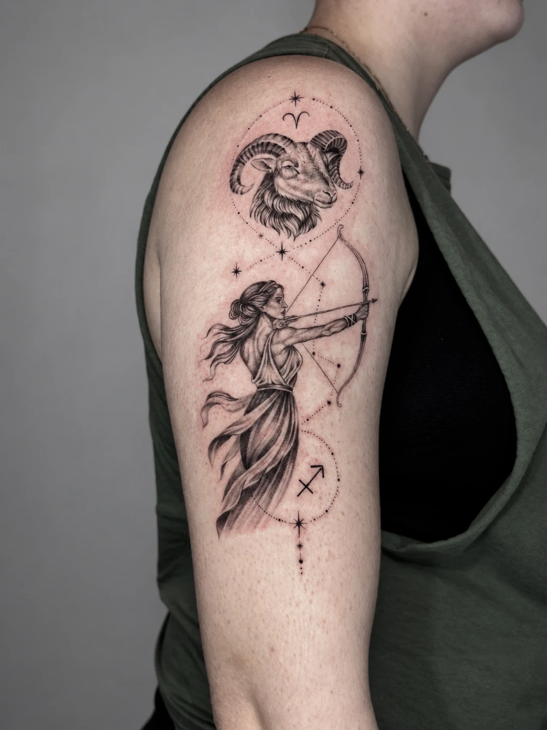Aries ram and Sagittarius archer linked by a constellation, tattooed on the upper arm