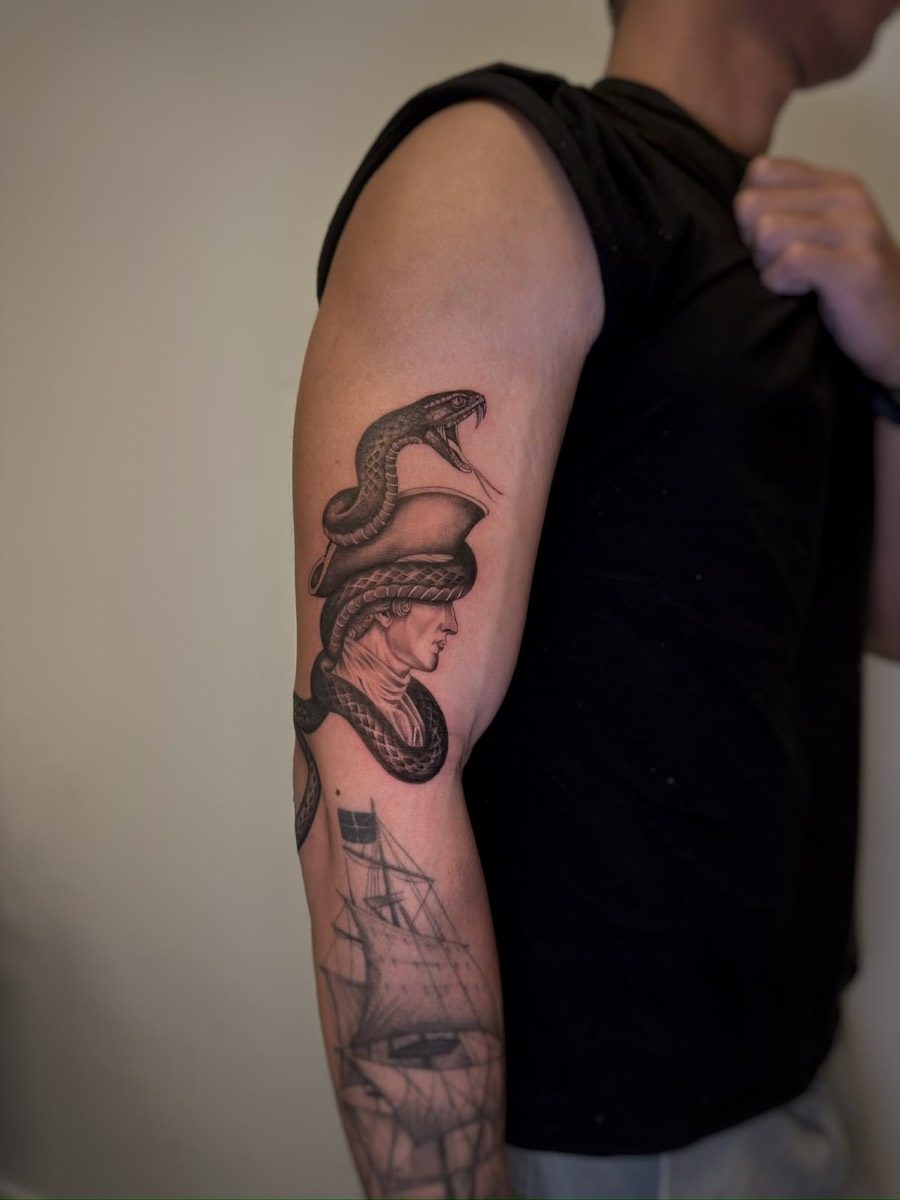 Classical helmet profile wrapped by a snake, tattooed on the upper arm
